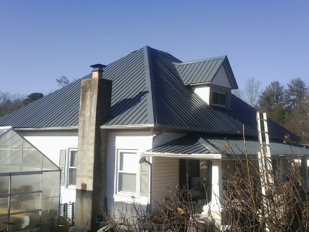 Dark blue standing seam metal roof on a white farmhouse with dormer — Slate & Tile Roof Repair by Roofing Brothers in Randleman