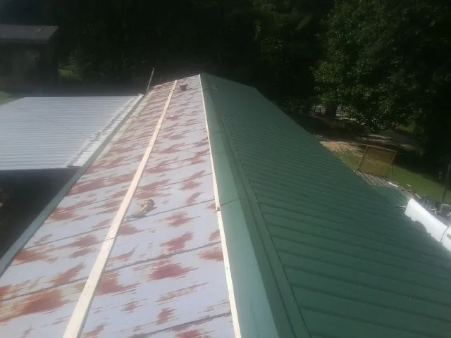 Old rusted panels beside newly installed green metal roofing — Wind Damage Roof Repair by Roofing Brothers in Randleman