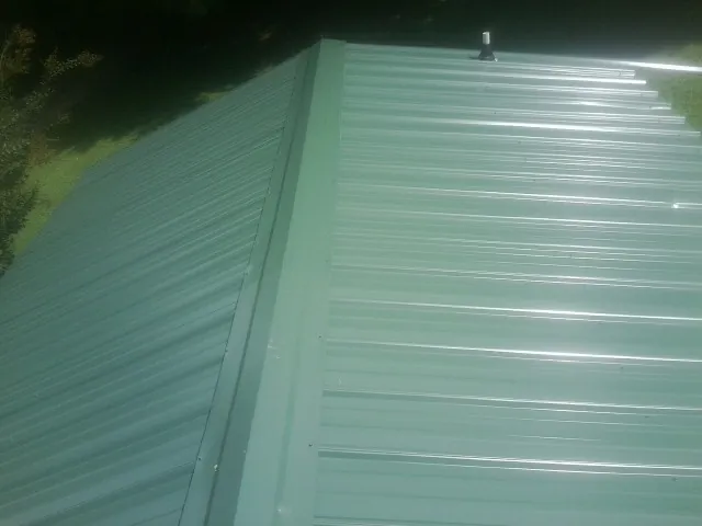 New green metal panels meeting at the ridge of a roof — Flat Roof Repair work by our crew in Randleman
