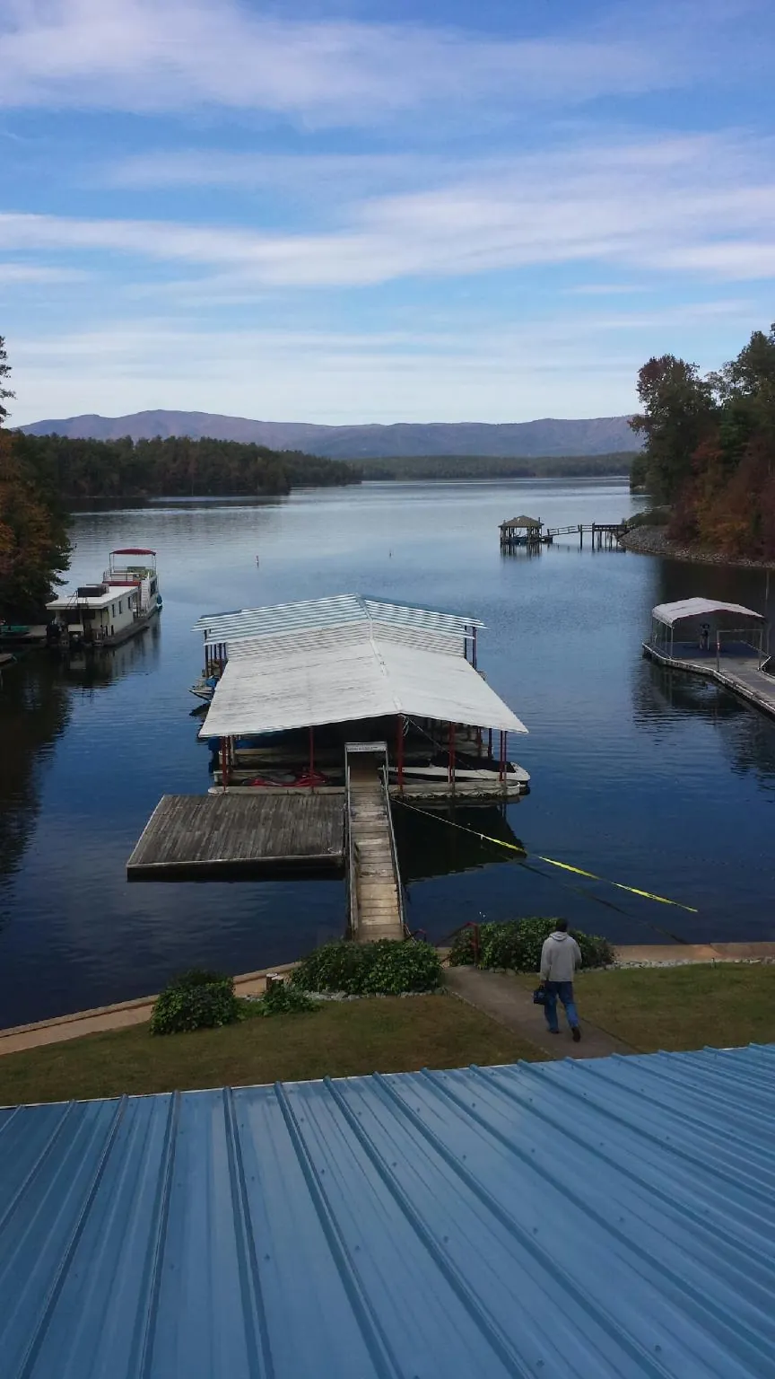 View across a lake from a newly installed blue metal roof in Randleman