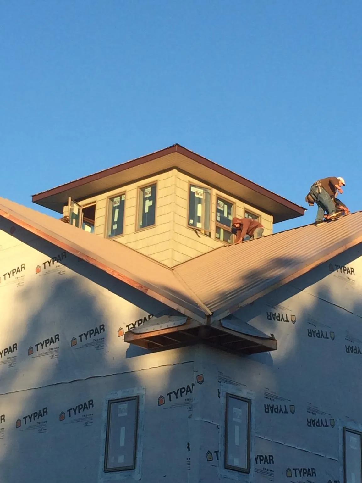 Roofers working around a rooftop cupola on a new metal roof at sunset — Roof Waterproofing in Randleman by Roofing Brothers